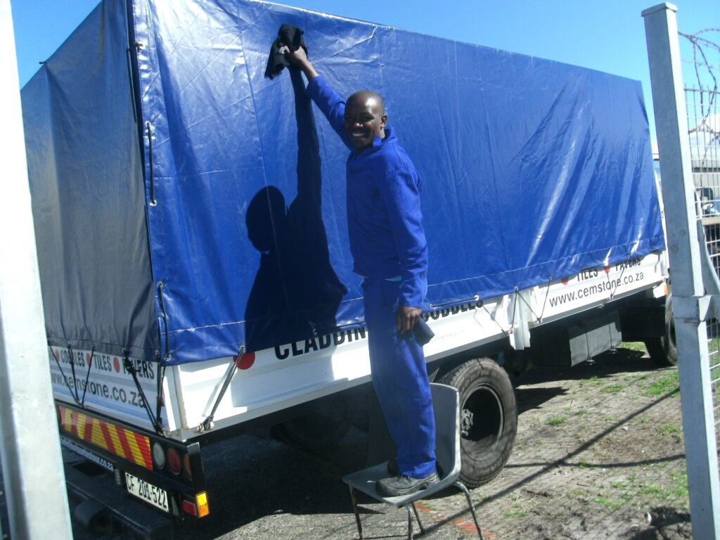 Man wiping down blue canvas cover of truck